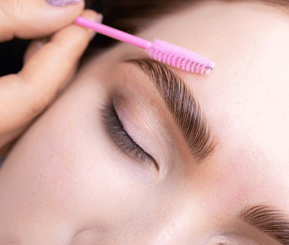 Close-up of a person getting eyebrow grooming with a spoolie brush.